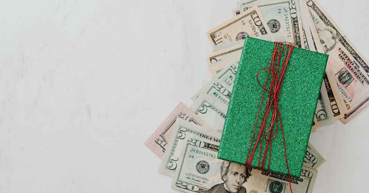 Green gift box on a pile of dollar banknotes showcasing a concept of monetary value and gift-giving.