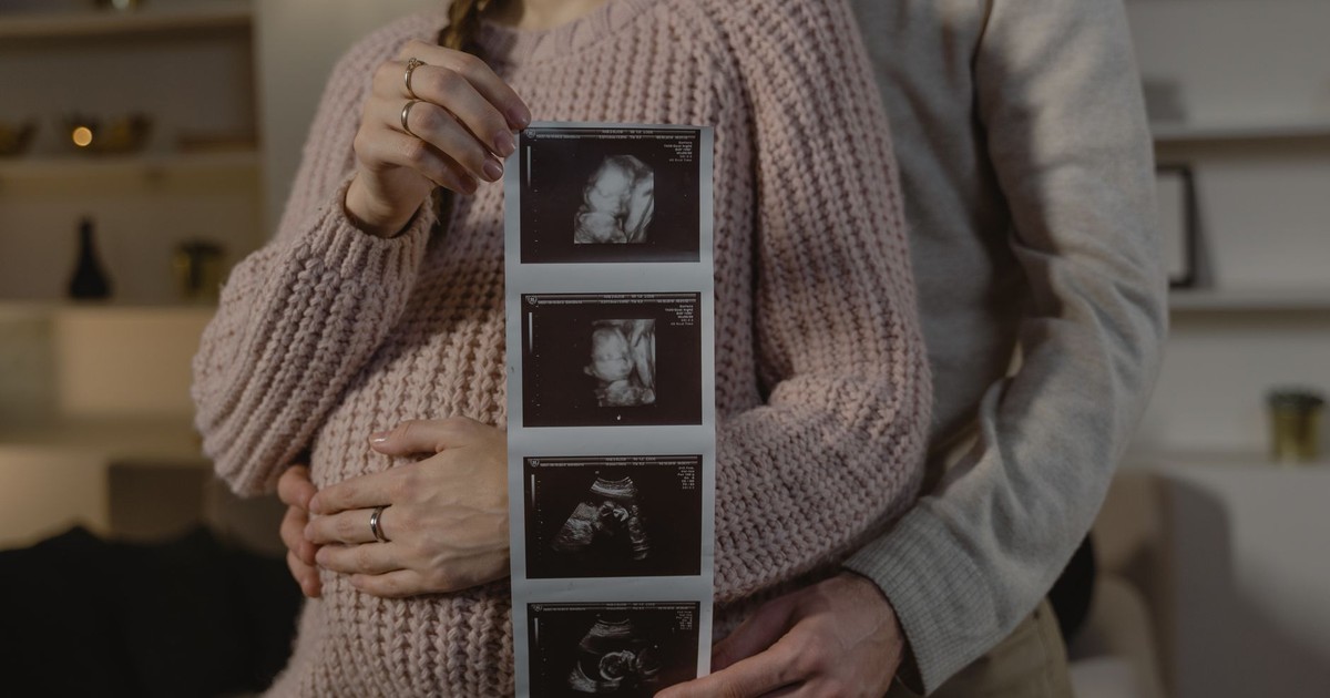 Expectant couple indoors holding ultrasound, symbolizing new life and family bonds.
