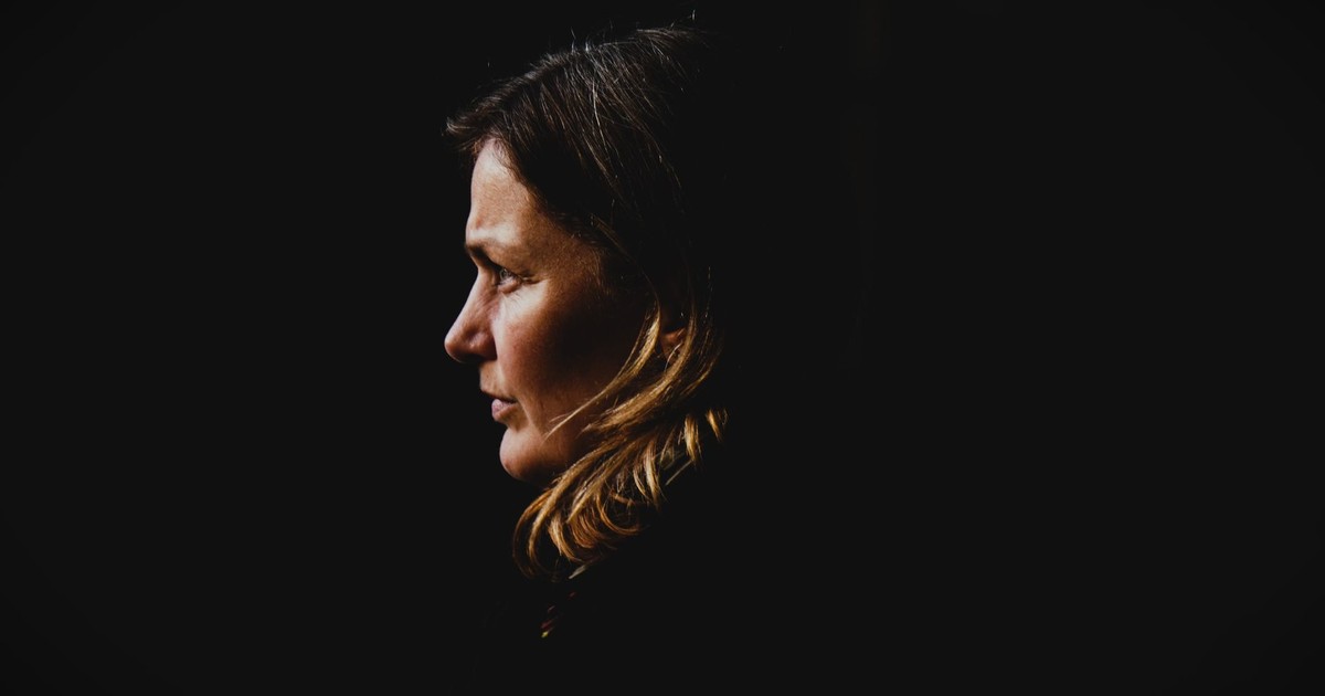 Side profile portrait of a woman with dark background, capturing introspection.