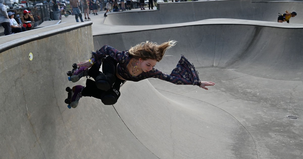 Young woman performing a roller skating trick in a skatepark, showcasing skill and agility.