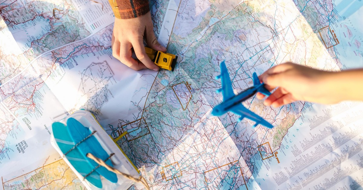 Hands holding a toy airplane and car over a map, symbolizing travel planning and exploration.