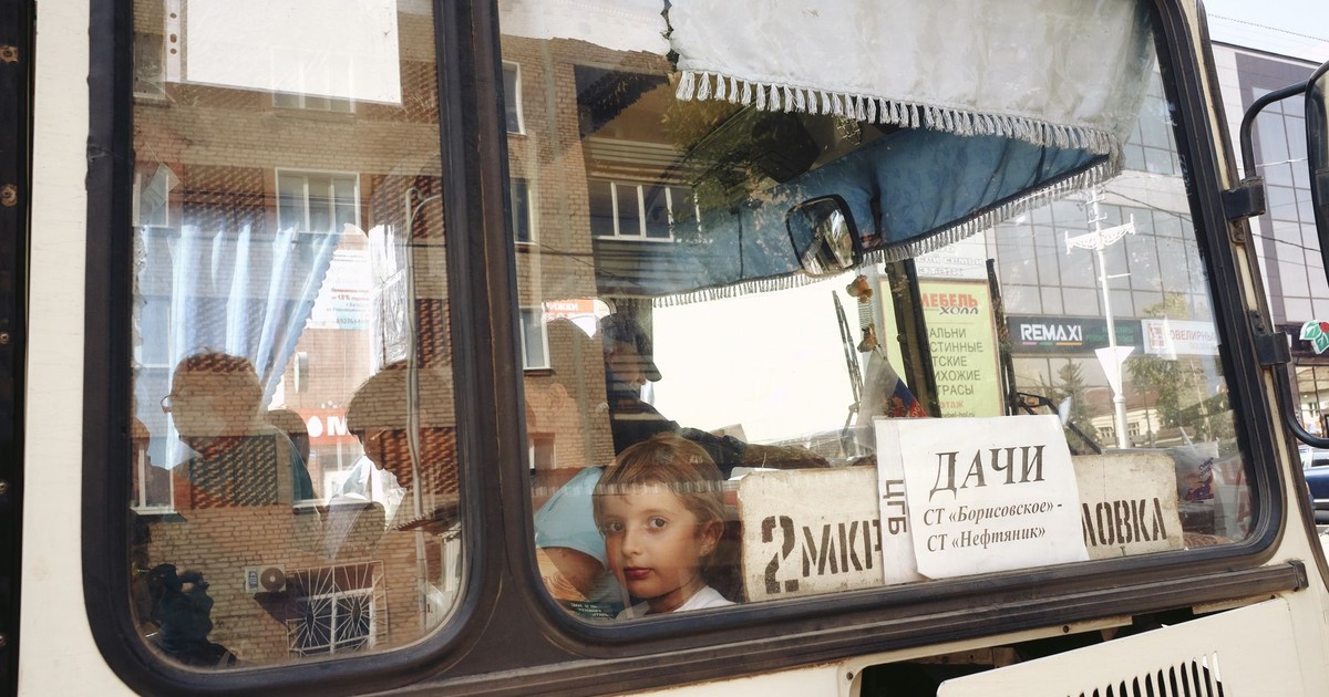 A child looks out the window of a public bus, reflecting urban life.
