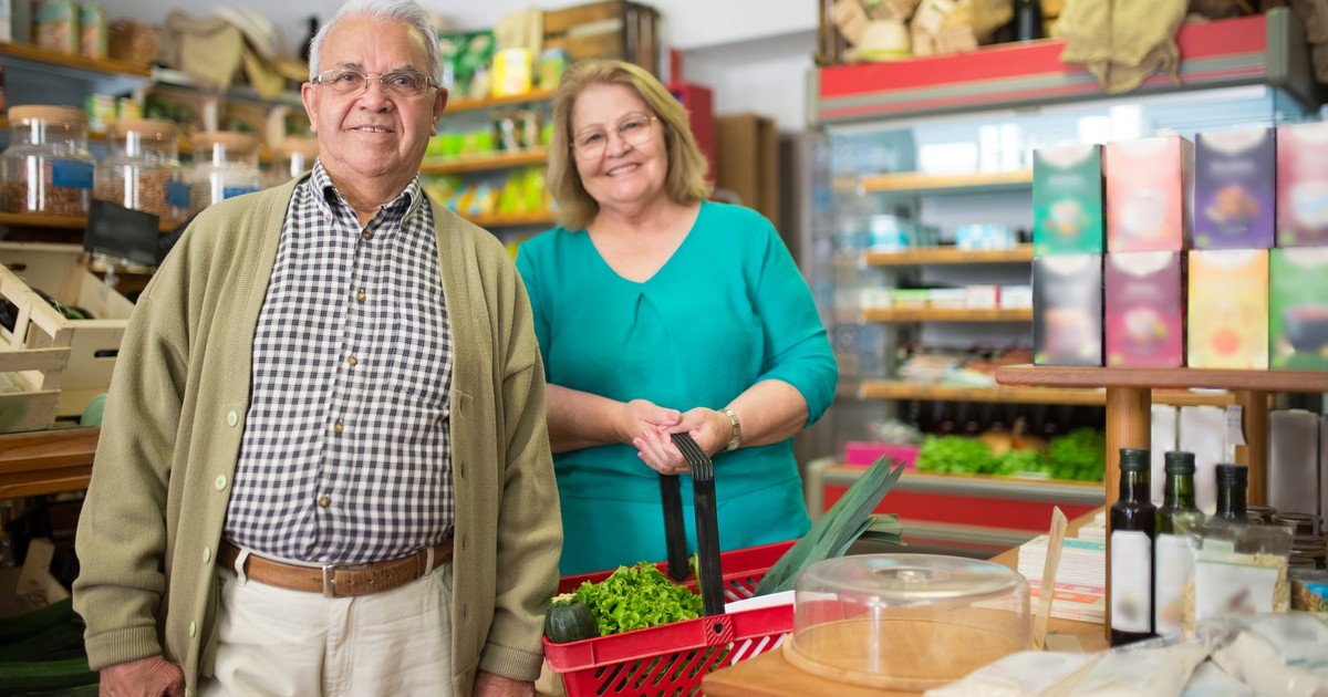 Elderly couple smiling while shopping at a local Portuguese grocery store.
