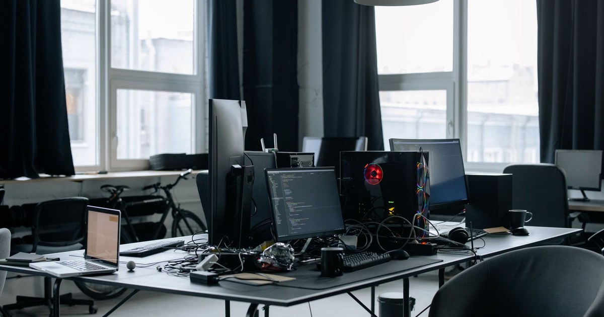 Contemporary workspace featuring computers, coding screens, and office essentials in a tech environment.