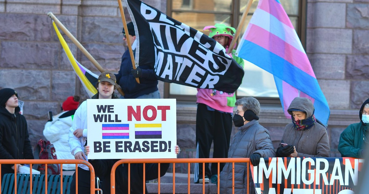 Protesters holding LGBTQ+ and BLM flags, advocating for rights and inclusion.