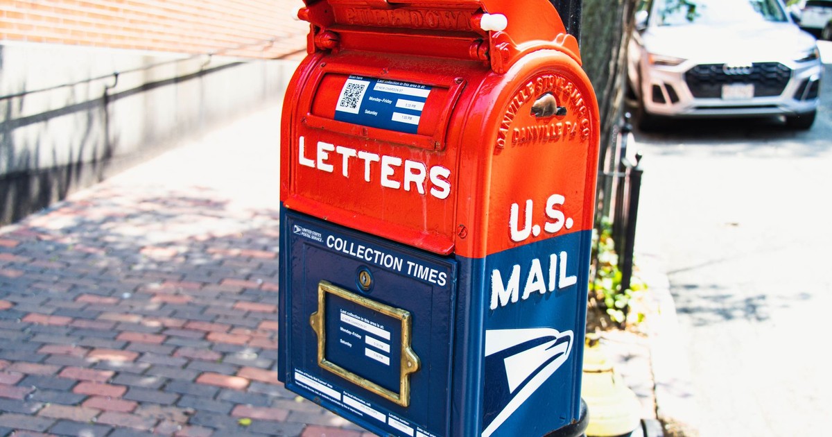 Vibrant U.S. mailbox on a city sidewalk with a parked car, conveying a classic urban scene.