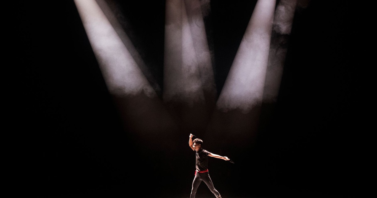 Energetic performance by male dancer under dramatic stage lighting.