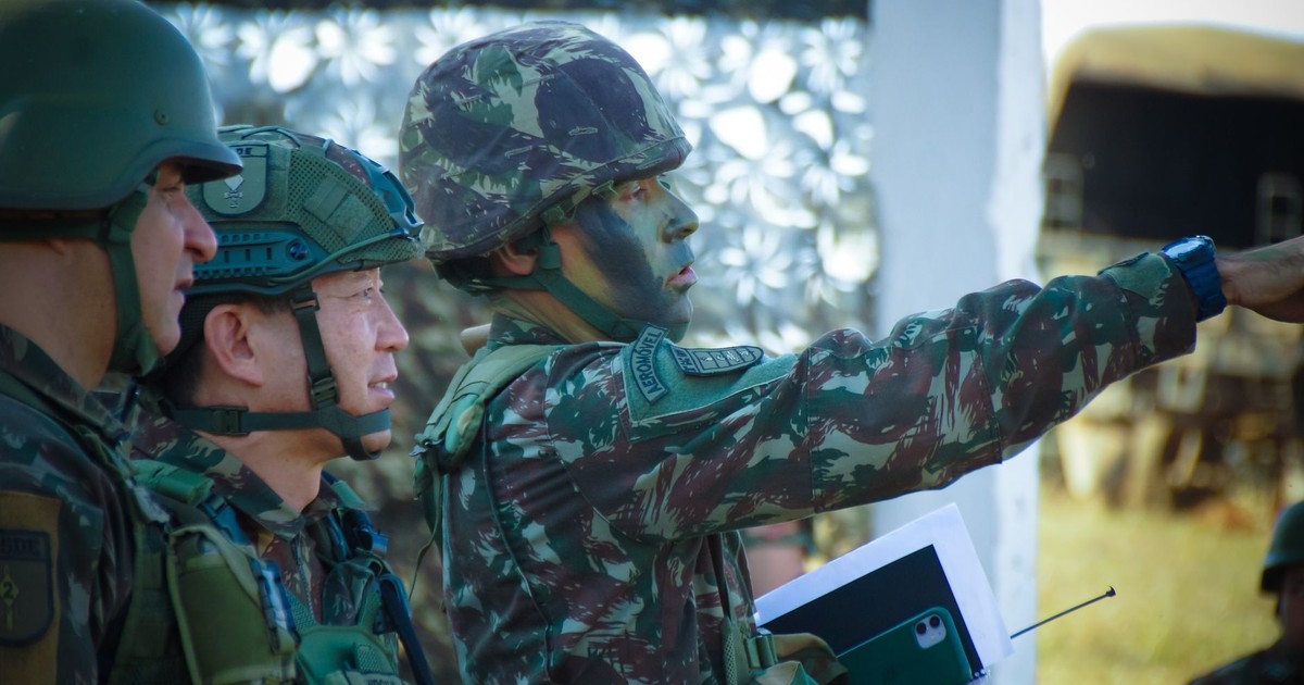 Soldiers in camouflage and helmets strategizing outdoors, focusing on a mission directive.