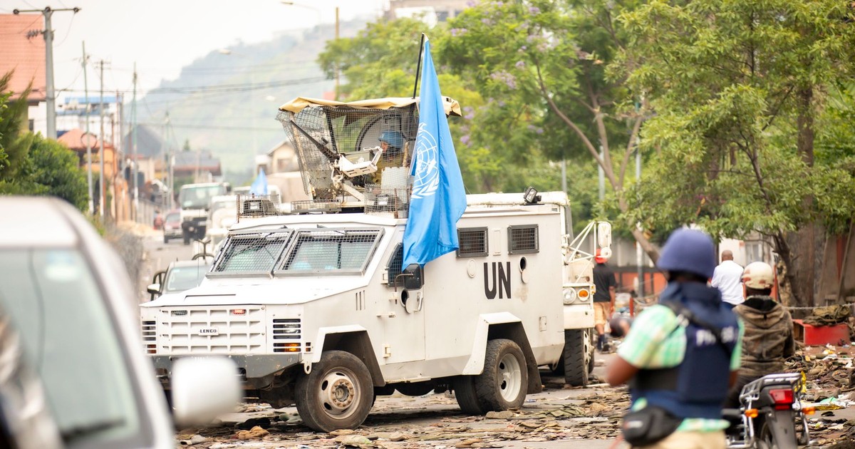 United Nations armored vehicle navigating street amid conflict. Peacekeeping and security presence.