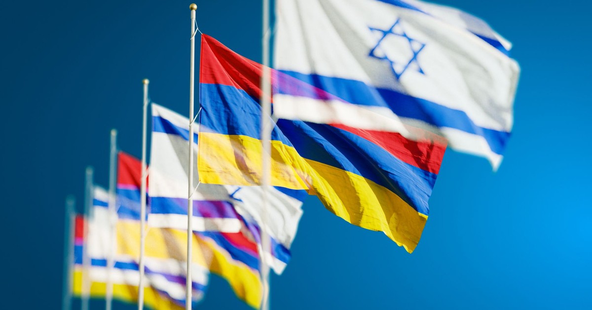 Vibrant national flags of Israel and Armenia waving against a clear blue sky.