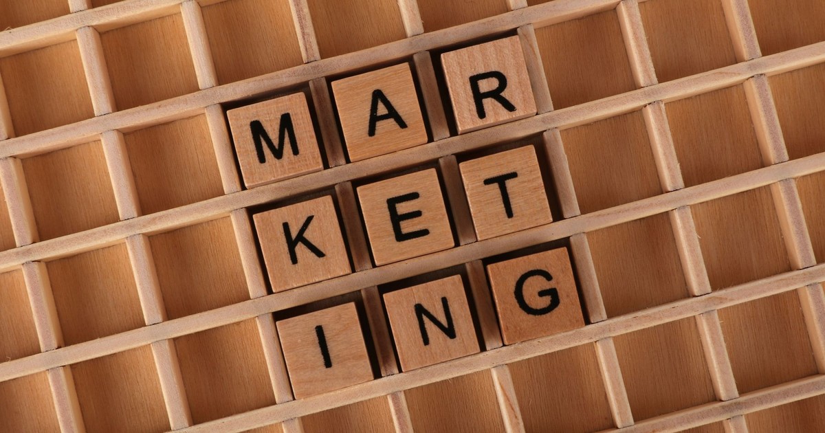 Wooden letter tiles spelling 'Marketing' on a wooden grid, emphasizing strategy and planning concepts.