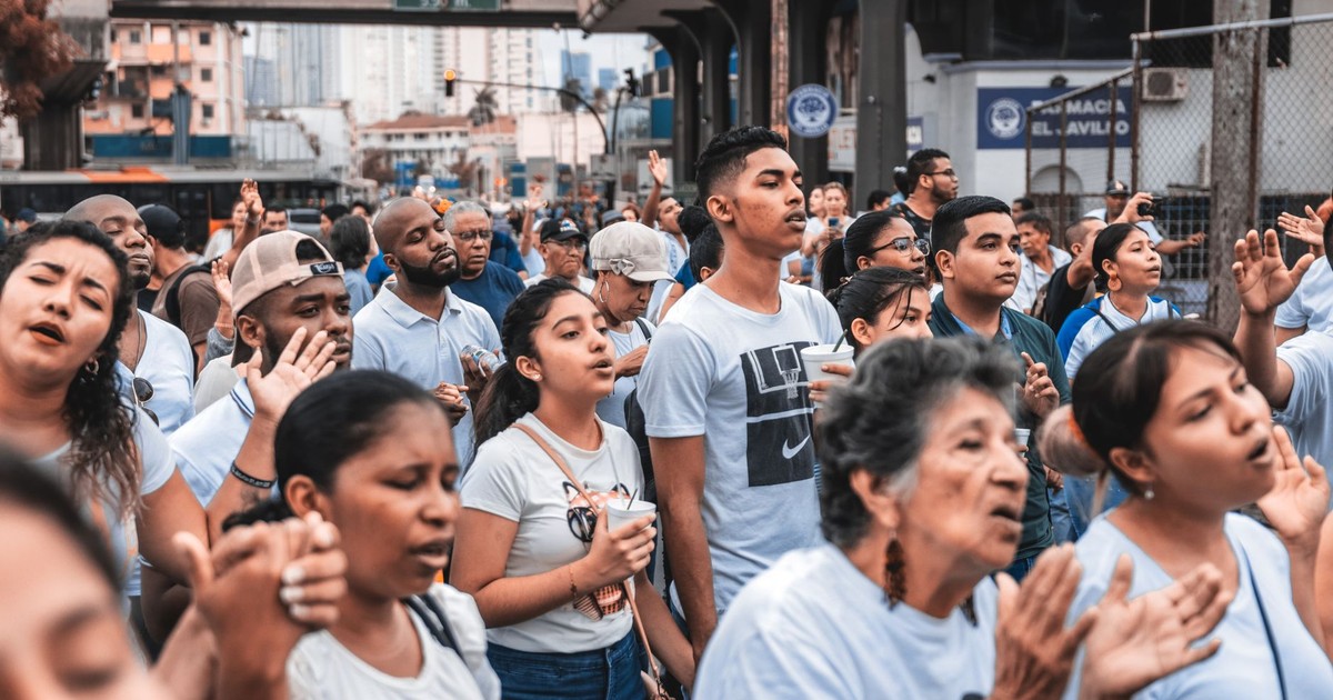 A large group of diverse people gathered outdoors, engaging in a community event in an urban setting.