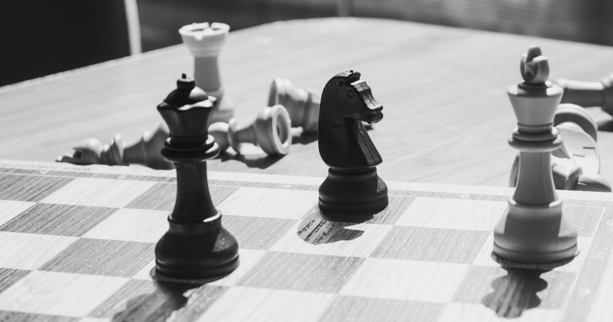 A black and white photo of chess pieces on a chessboard, capturing a strategic moment.