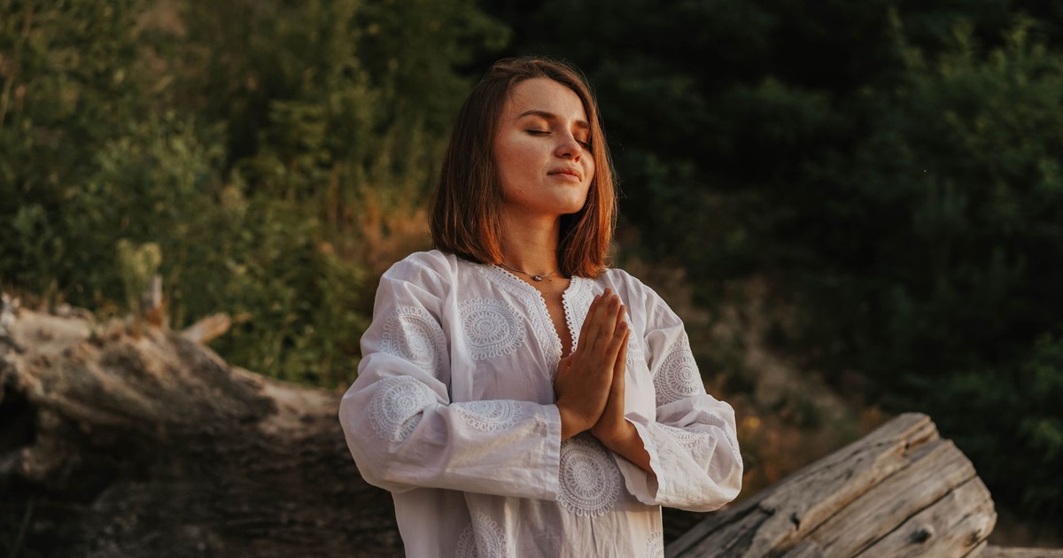 A woman with short hair meditates outdoors, embracing tranquility amidst nature.