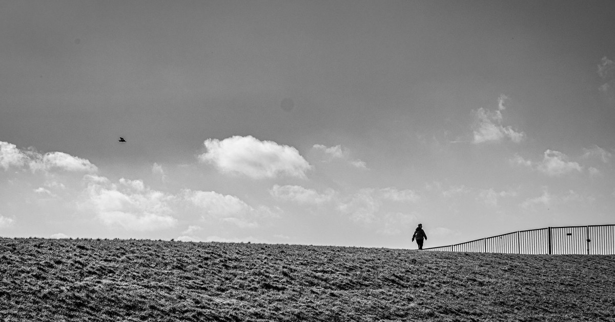 Black and white photo of a solitary person on a hill with wide open skies.