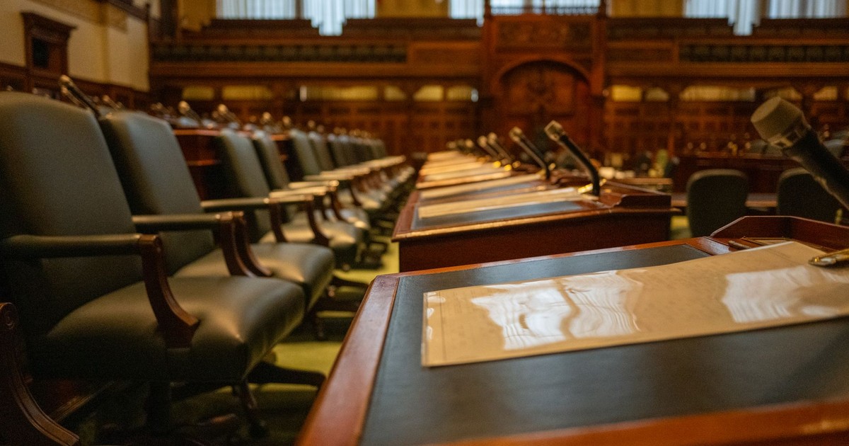 A detailed view of an empty legislative chamber with rows of desks and microphones, evoking governance.