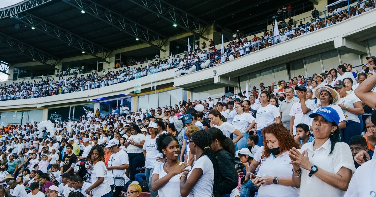 A vibrant crowd gathers in a stadium, enjoying an exciting event under a covered roof.