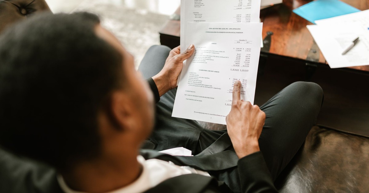 Business professional examining financial documents, focusing on analytics and paperwork in an office setting.