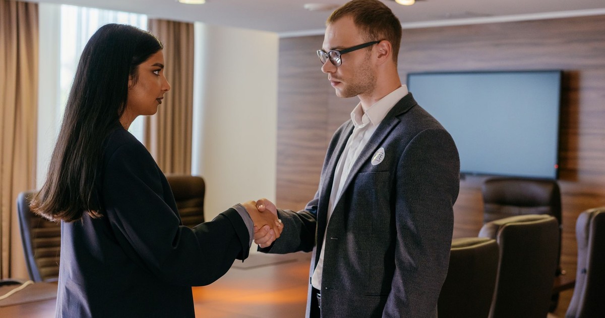 Two professionals shaking hands in a modern conference room, symbolizing successful business agreement.