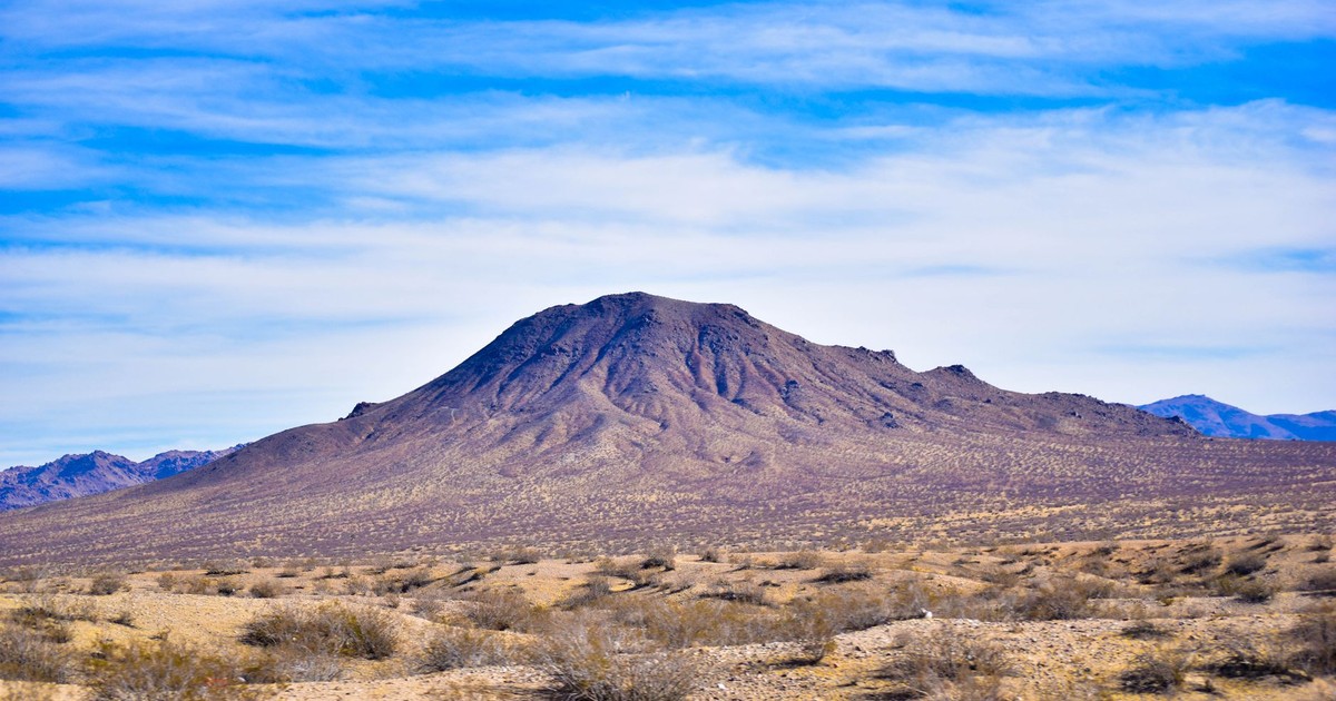 A striking mountain in the arid desert landscape of Nevada under a vast blue sky.