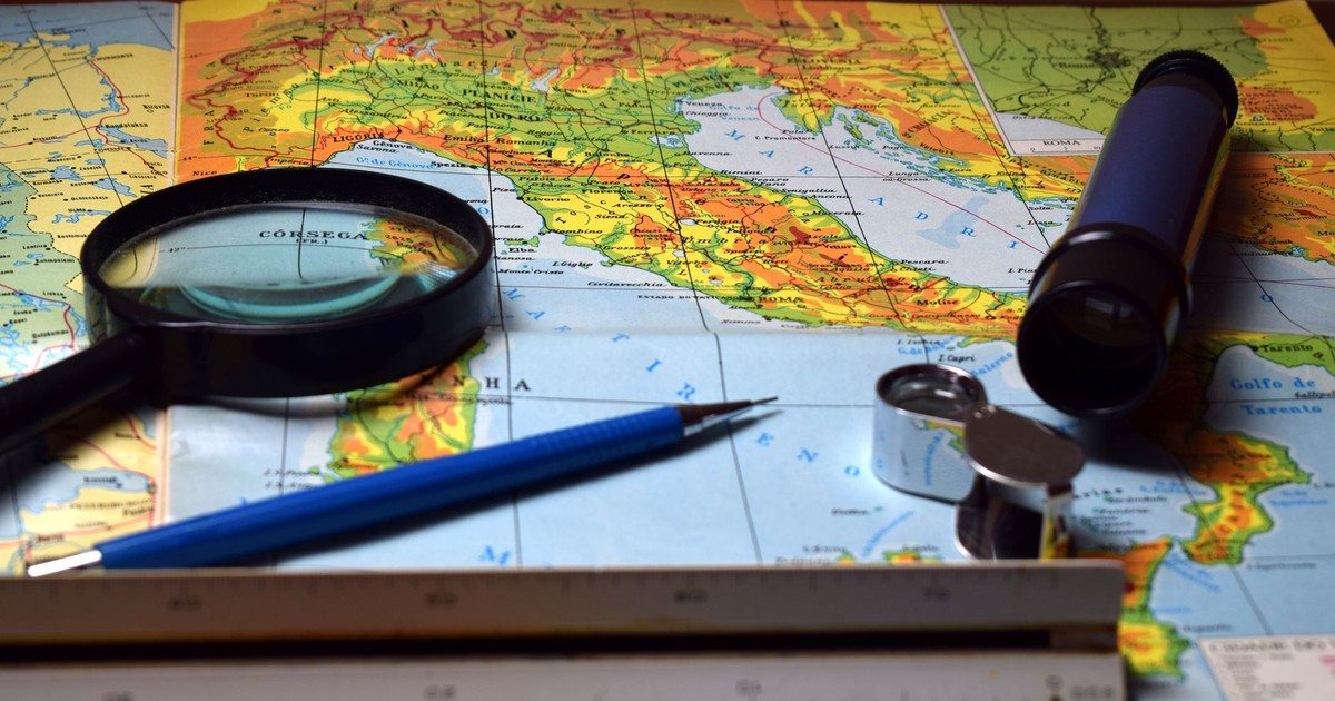 Magnifying glass and tools on a colorful map, perfect for travel and exploration themes.