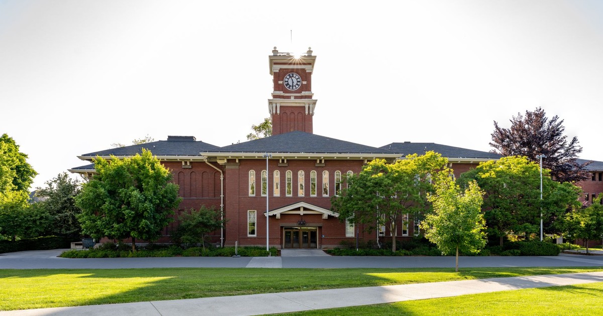 Historic clock tower at WSU Pullman campus surrounded by green lawns and trees.