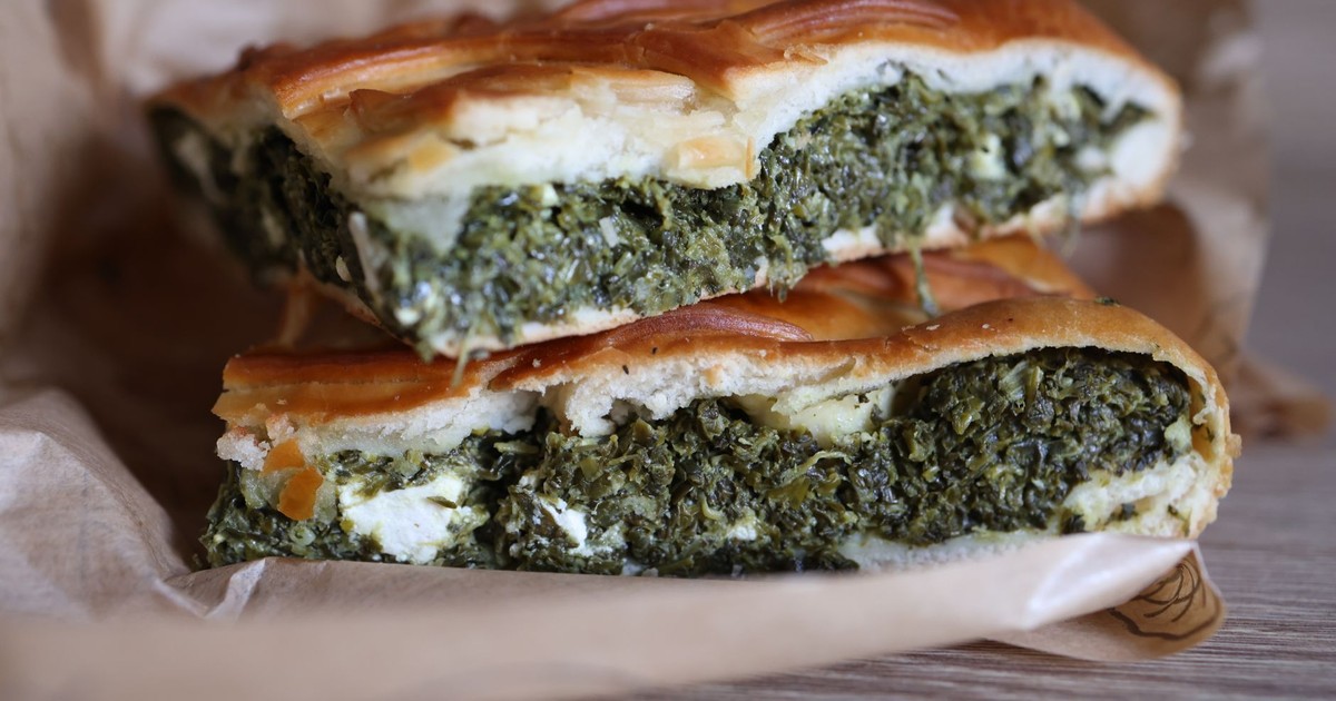 Close-up of fresh spinach and feta spanakopita slices on parchment paper.