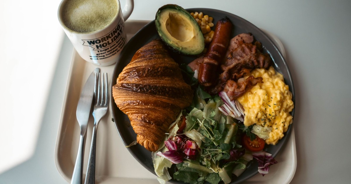 Delicious breakfast plate with croissant, scrambled eggs, and coffee in a cozy setting.