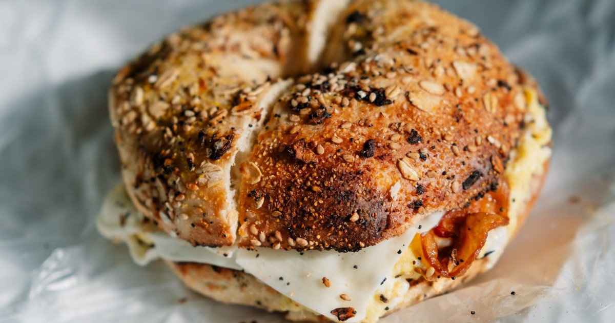 Close-up of a savory everything bagel sandwich stuffed with egg and bacon.