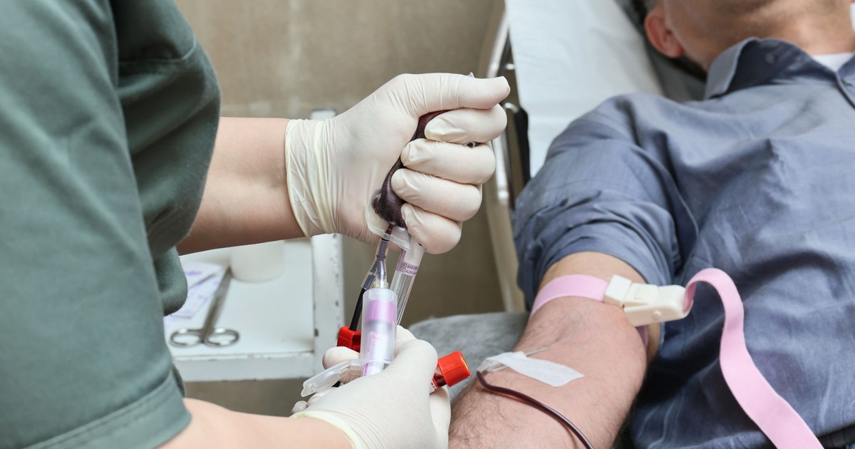 A healthcare professional drawing blood from a donor’s arm using a syringe.