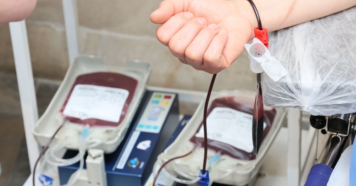 Close-up of blood donation process showing a donor's arm and blood bags in a clinic.