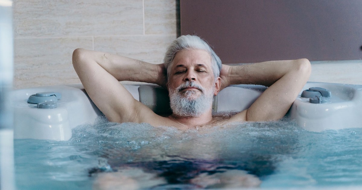 Elderly man with grey hair enjoying relaxation in an indoor jacuzzi.