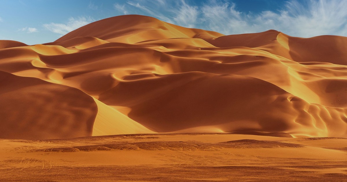 Stunning golden desert dunes under a bright blue sky, perfect for nature wallpapers.