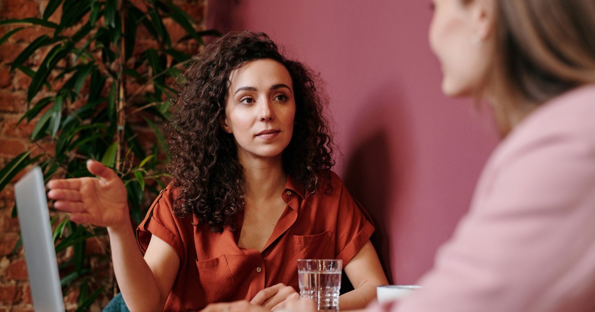 Two women discuss business ideas in a cozy café setting.