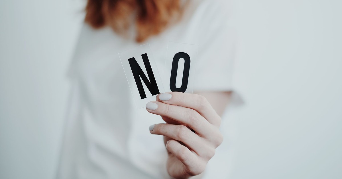Close-up of a person holding a "No" sign, symbolizing rejection or disagreement.