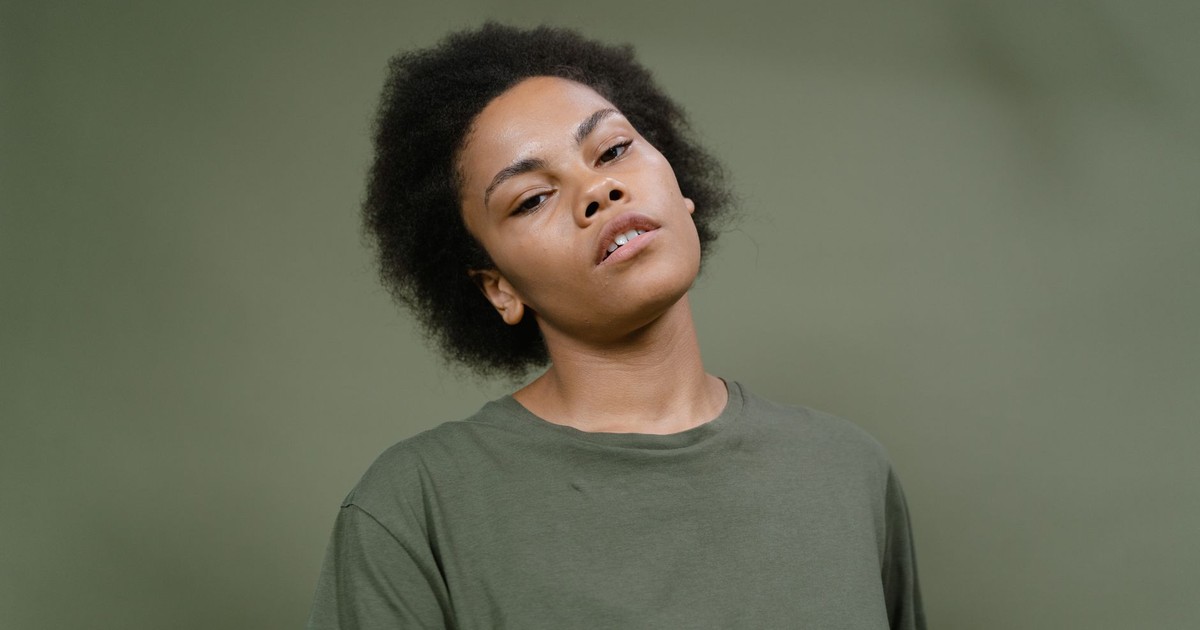 A striking portrait of a woman with natural afro hair against a solid green background, exuding confidence.