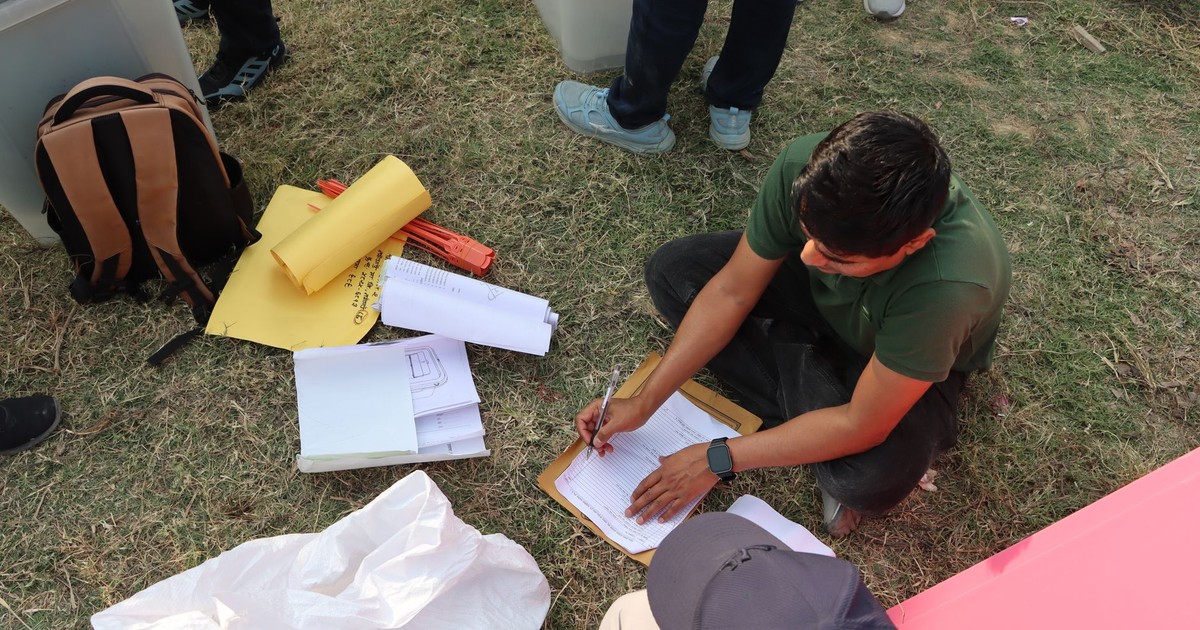 Man sorting electoral papers outdoors in Nepal for upcoming election.