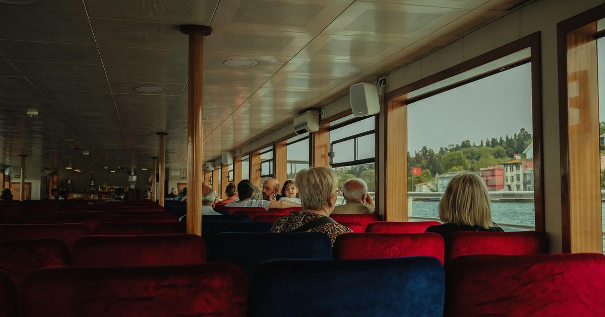 Experience the tranquil ferry ride with passengers enjoying the scenic view outside.