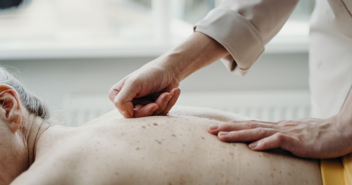 Close-up of hands massaging a person's back, showcasing relaxation and skin health.
