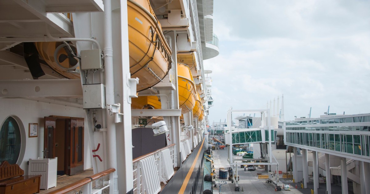 A detailed view of life boats on a docked cruise ship at a port, showcasing maritime safety equipment and infrastructure.