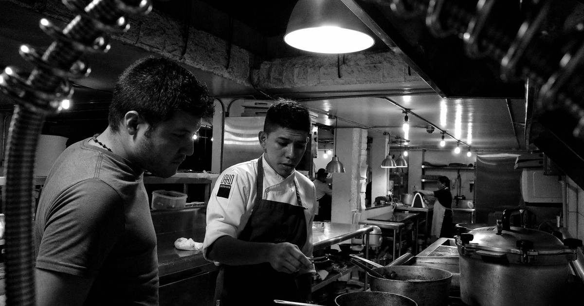 Chefs working attentively in a restaurant kitchen, collaborating over stove preparations.