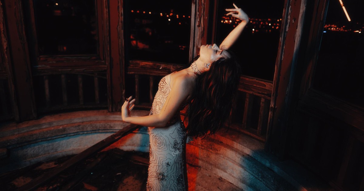 A woman in an elegant gown dances gracefully in an ambient, moonlit setting.
