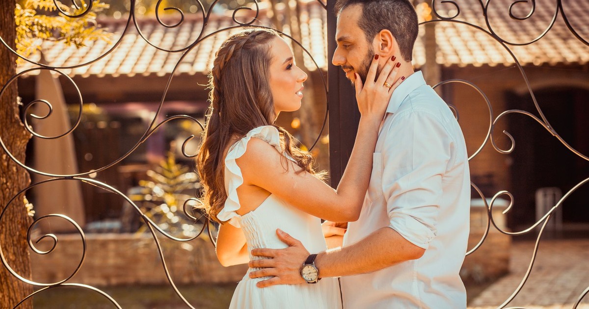 A couple sharing an intimate moment outdoors with a beautiful gate backdrop, captured in warm tones.