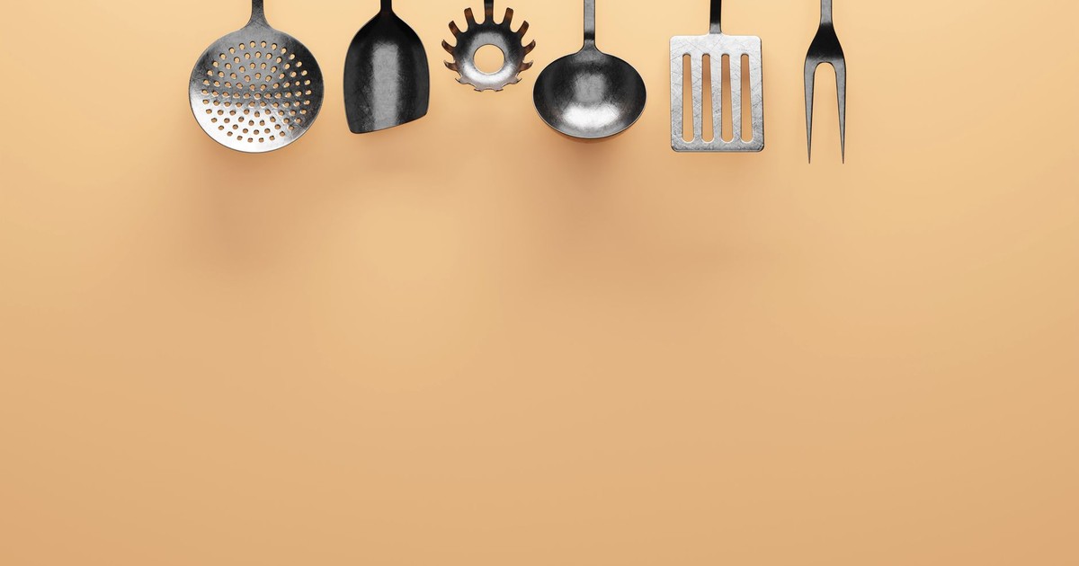 Display of various stainless steel kitchen utensils on an orange background.