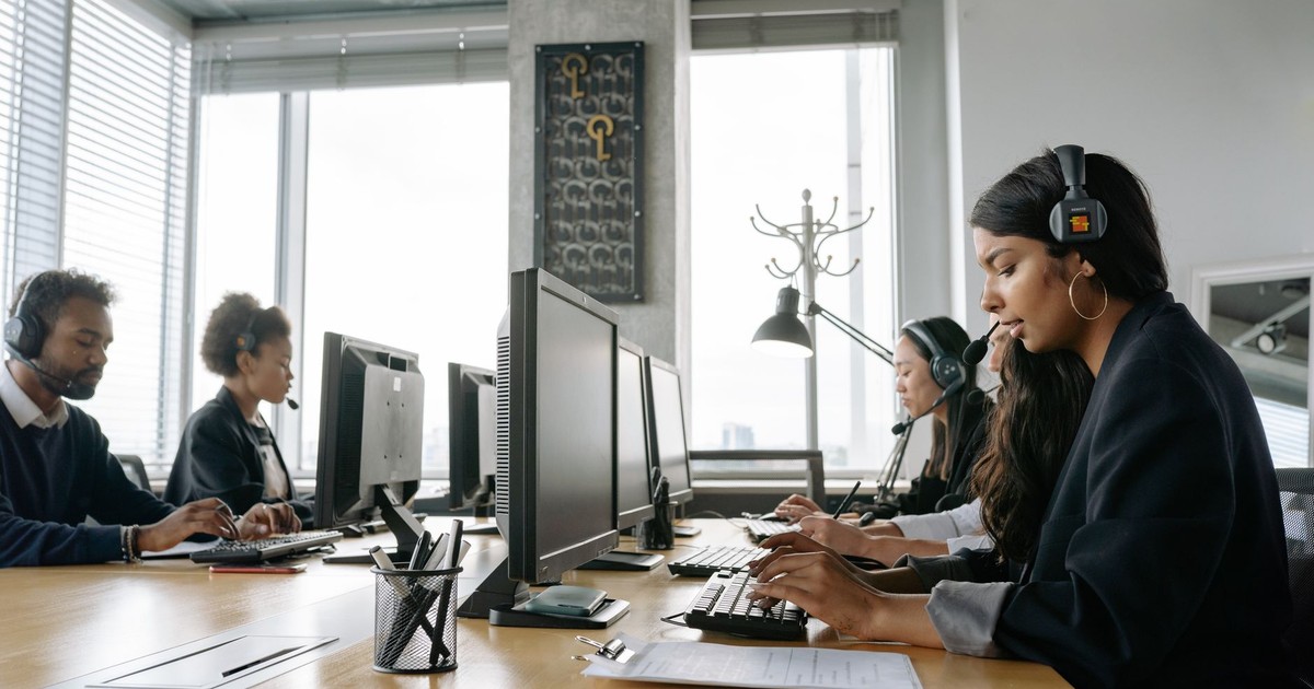 A team of call center agents working in a modern office with headsets and computers.