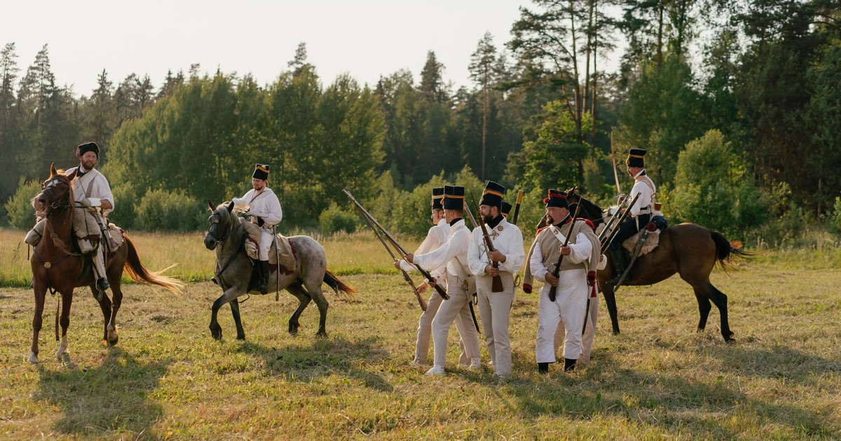 Group of reenactors depicting historical soldiers in uniform with rifles and horses.