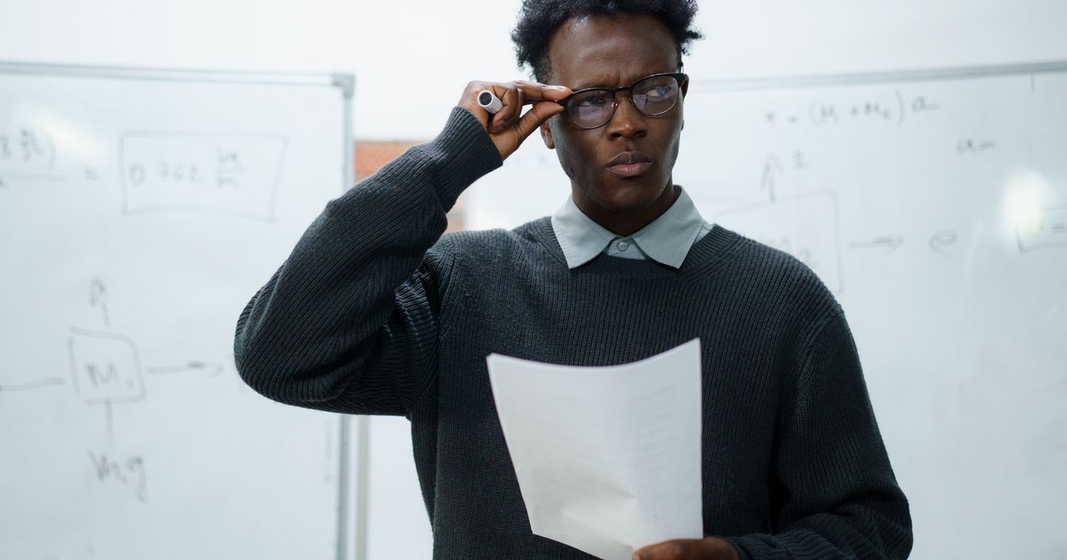 Focused businessman reading documents in an office setting with whiteboards.