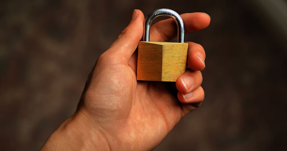 Hand holding a brass padlock, symbolizing security and protection