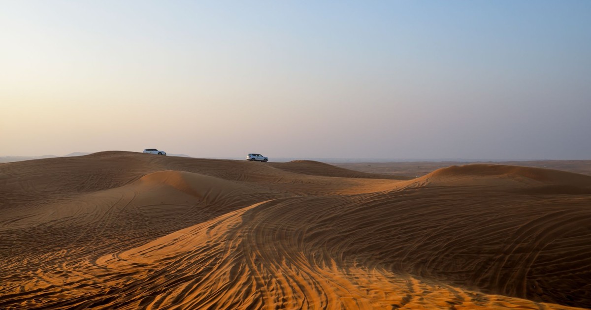 Traversing the serene desert dunes by car, capturing the essence of a desert safari at dawn.