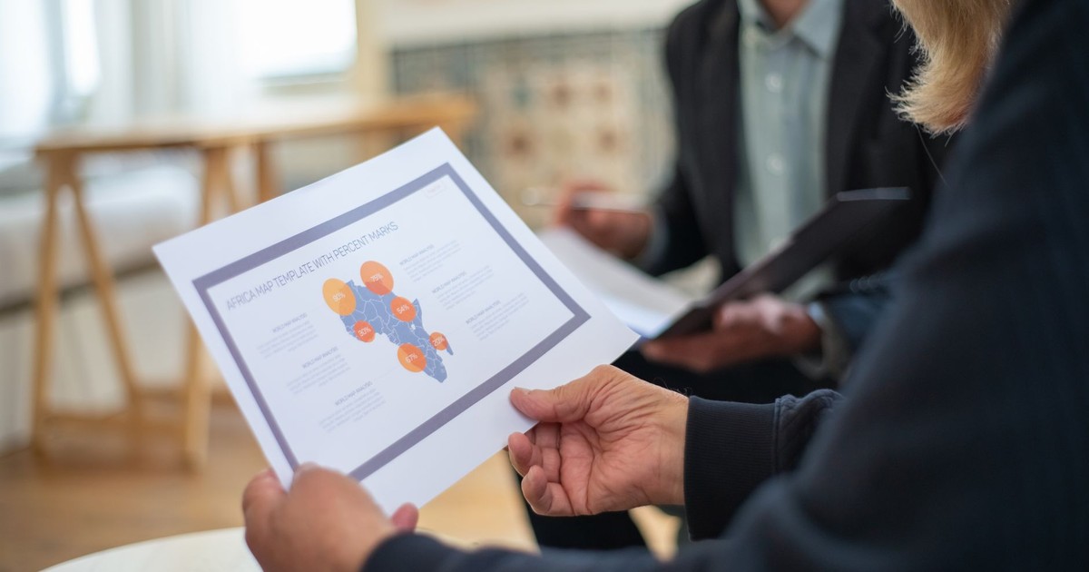 Three professionals discussing a data presentation in an office setting.